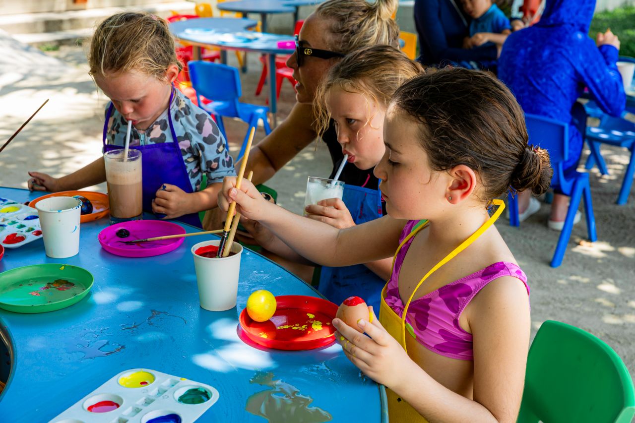 services-04 Children painting at an outdoor event while sipping refreshing beverages. Creative and joyful atmosphere.