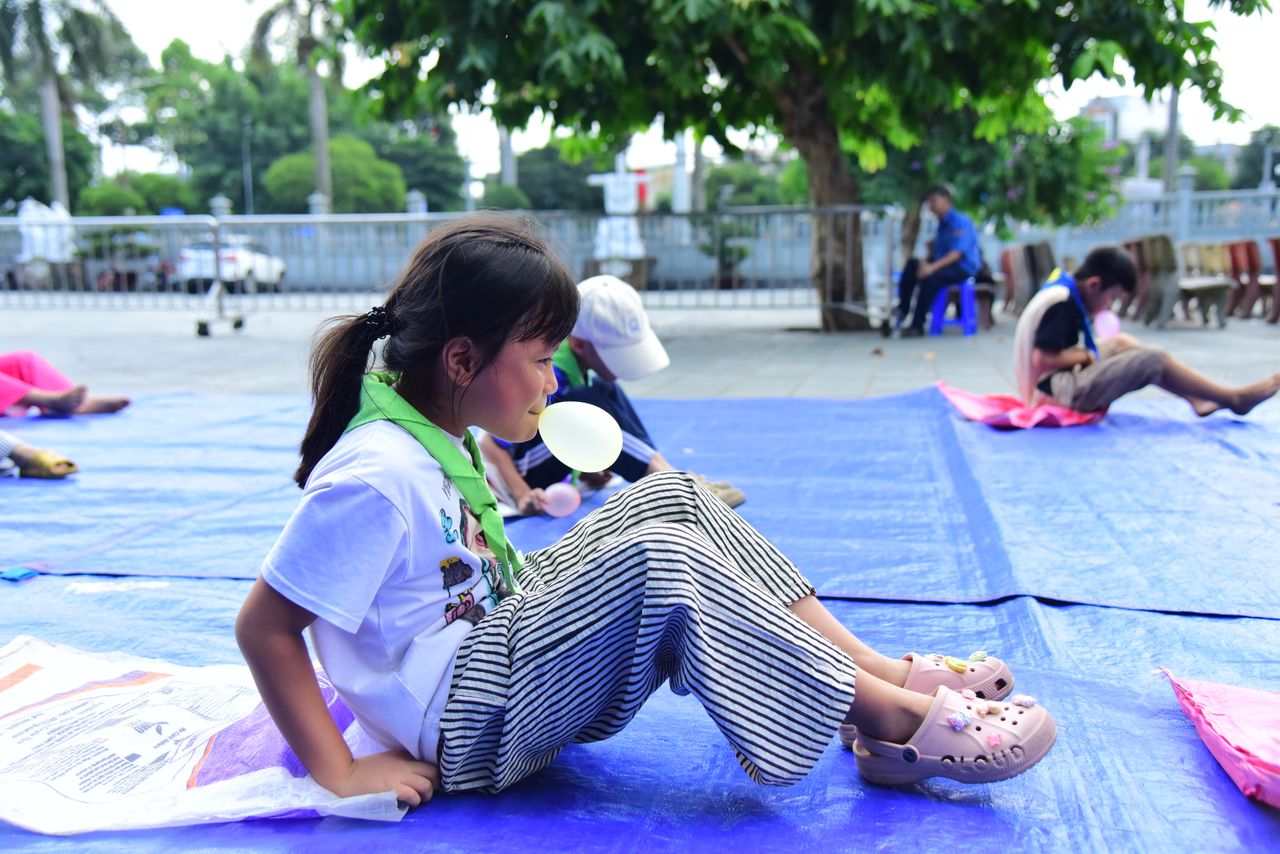 services-01 Kids play games on outdoor mats in a sunny park setting, enjoying fun activities.